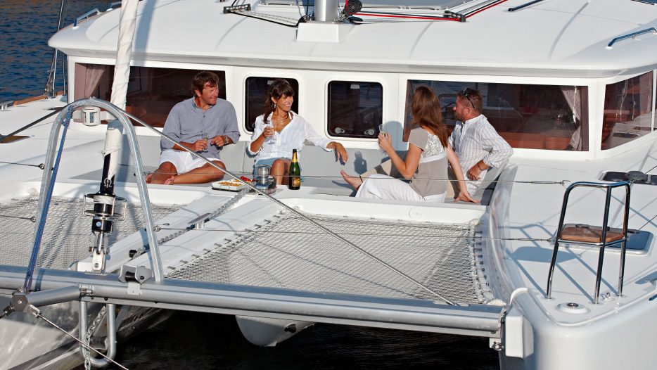 Lagoon 450 Fly front view of boat with people and trampolines